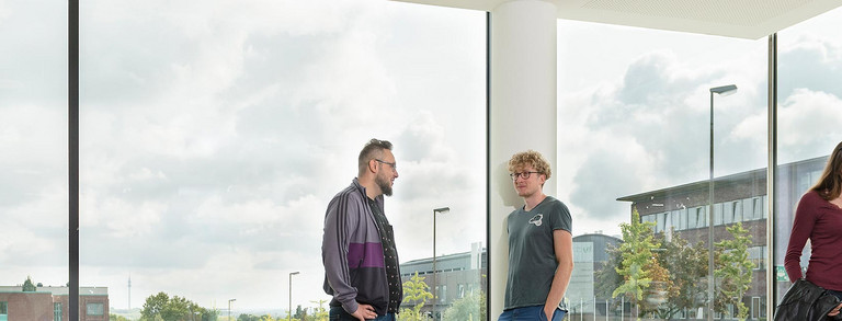 Students are talking in front of a window